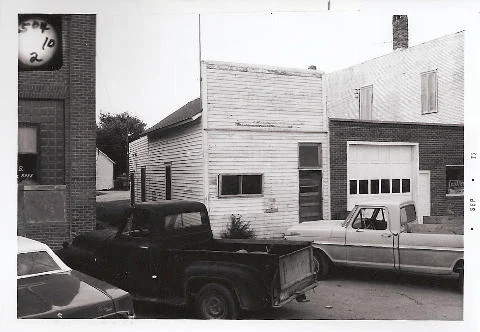 Historic pickup trucks parked along a building in Verona, ND